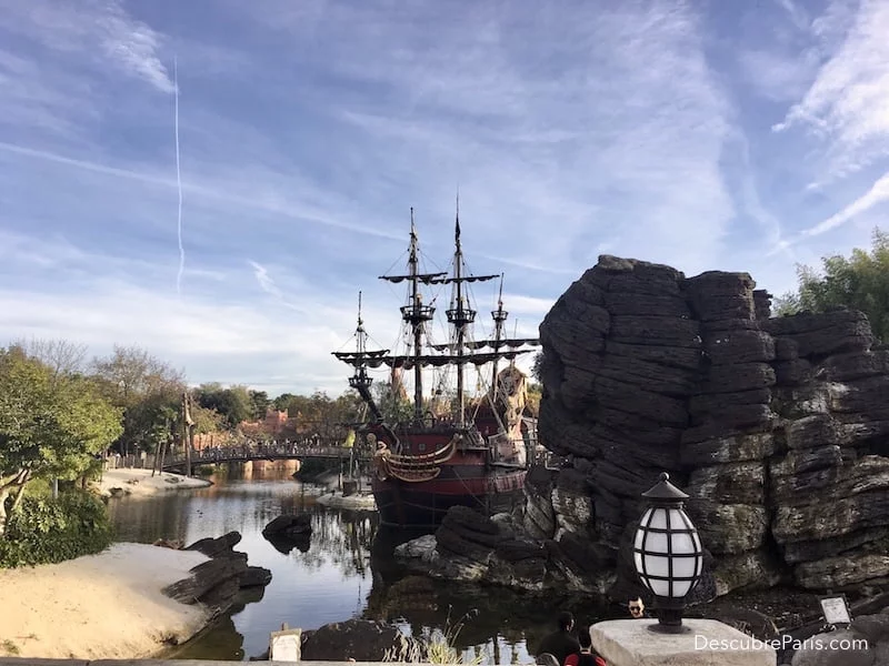 Playa de los Piratas. Disneyland Paris. Se ve un barco pirata al lado de unas grandes rocas y una playa